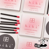 多個粉色漸層包裝盒，盒上印有「hibi 10MINUTES AROMA TAIWAN LIMITED MADE IN JAPAN」字樣及圖案。旁邊擺放著數支黑色木質火柴，頂端有紅色火藥頭。