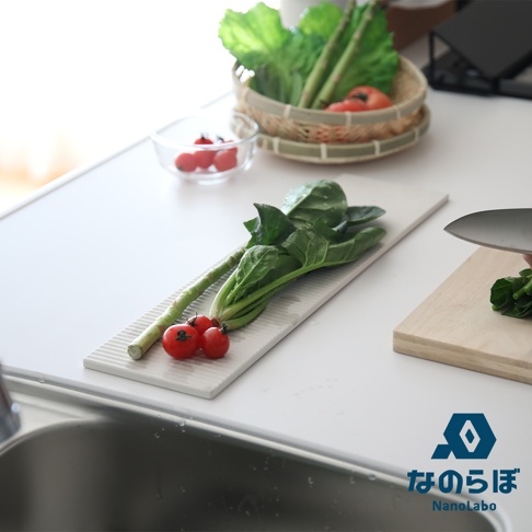 長形白色珪藻土吸水置物墊上擺放著綠色蔬菜、蘆筍及兩顆小番茄。
