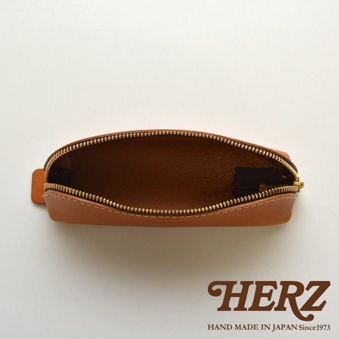職人手作皮革三角收納筆袋，展示為淺棕色，材質為皮革，拉鍊為金色，內裡為深棕色皮革。