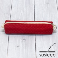 紅色三河木綿刺子織筆袋，帶有米白色拉鍊和掛環，置於淺色木紋背景上。