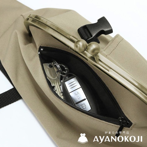 AYANOKOJI 品牌標誌旁顯示「がま口の専門店舗 AYANOKOJI」日文，圖片展示了一個卡其色斜背包側面，內袋拉鍊拉開，露出裡面的一串鑰匙和一個汽車遙控器，包包上還有一個金屬鍊條的口金、一個黑色塑膠扣。