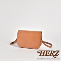 職人手作皮革翻蓋橫式單肩包，採用天然皮革材質，呈現淺棕色，縫線清晰，帶有可調節的肩帶，包身線條簡潔。