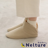 一雙米色網格紋路的保暖腳踝室內拖鞋，鞋面材質柔軟，鞋口設計包覆腳踝，搭配同色系襪子，整體呈現溫馨舒適的居家風格。