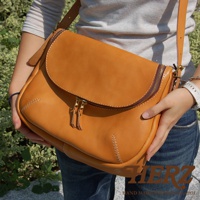 日本HERZ手工皮革大容量馬鞍包，焦糖色，採用拉鍊開合，由一位女士展示。