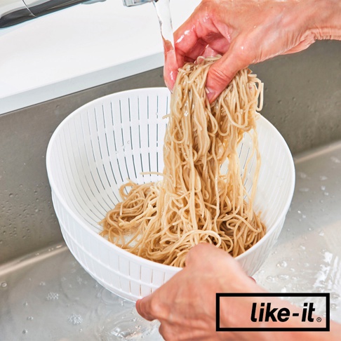 白色雙層瀝水籃，上方裝有麵條，正被水沖洗。