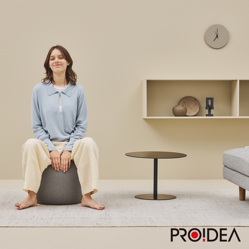 一位年輕女子坐在深灰色針織彈力平衡球迷你款上，此款平衡球採用耐磨針織材質，適合居家收納與運動。