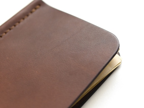 職人手作皮革短夾，深棕色，橫式對折設計，展現細緻的皮革紋理與車縫細節，部分內頁露出。