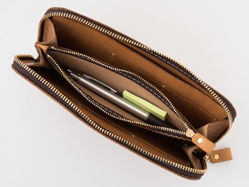 職人手作皮革大容量拉鍊長夾 (WL-5)，打開狀態，展示內部結構，包含一個銀色金屬筆和兩張淡綠色便條紙。長夾採用棕色皮革製作，配有金色拉鍊和皮革拉環。