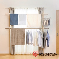 木紋頂天立地窗框曬衣架，設有兩層掛桿，上層掛有藍色、白色、米白色毛巾，下層掛有淺色系衣物，另有小型曬衣夾掛著襪子。