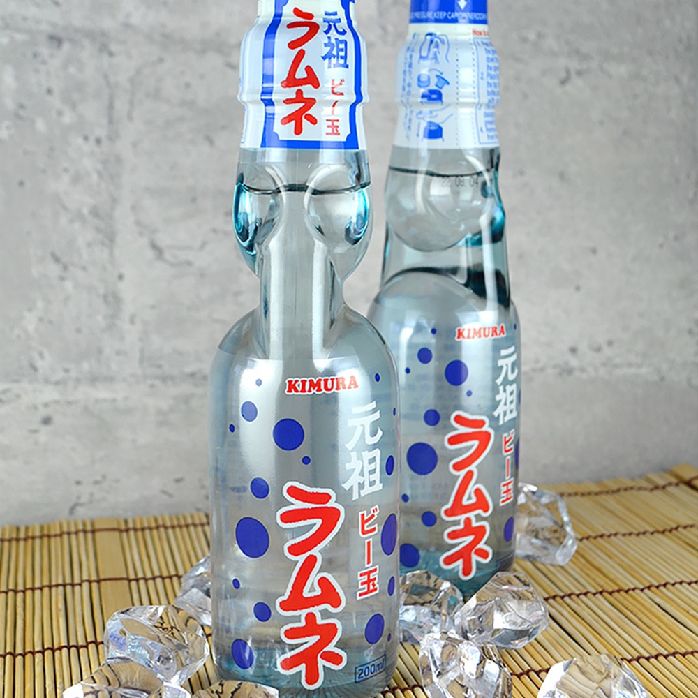 兩瓶日本元祖彈珠汽水，玻璃瓶身，淺藍色，瓶身印有紅色日文「ラムネ」及藍色圓點圖案，瓶頸處有白色與藍色相間的標籤。