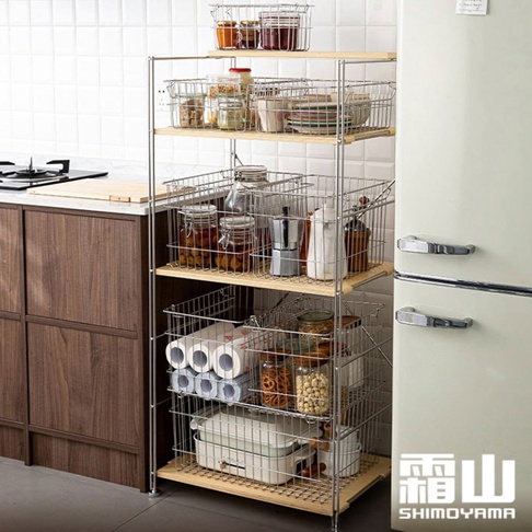 60公分寬、不鏽鋼三層收納置物架，層板為淺木色，架子上方置物籃內有玻璃罐裝食品、碗盤、咖啡壺、白色瓶子等物品，下方置物籃內有衛生紙捲、零食罐、電器等。