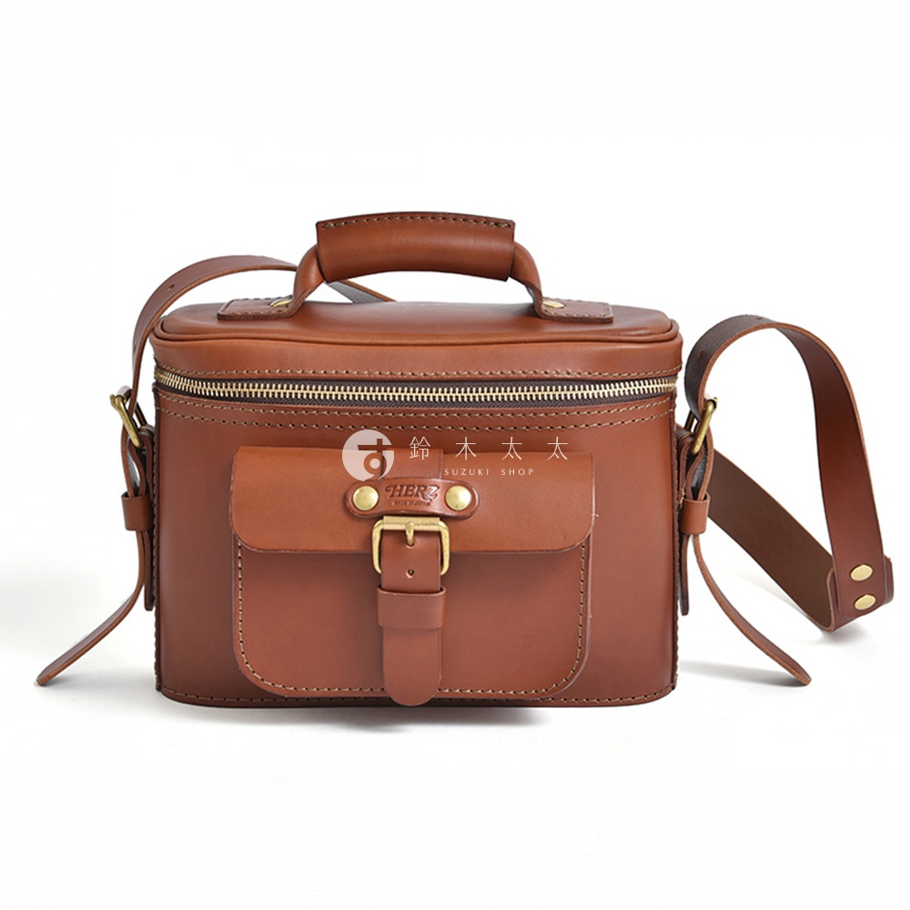 日本HERZ職人手作咖啡色皮革相機包，帶有金屬扣環的翻蓋前袋和頂部拉鍊開口，側邊有可拆卸的長背帶。