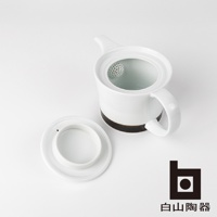 白色陶瓷茶壺，帶有咖啡色麻紋底座，壺蓋敞開，露出內部濾網。