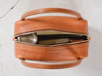 職人手作皮革Organ方形托特包 (G-47) M，採用淺棕色紋理皮革製成，方形簡約設計，頂部有拉鍊開合，露出內部筆記本和金屬隨身瓶。包身兩側有對稱的提把，縫線清晰。