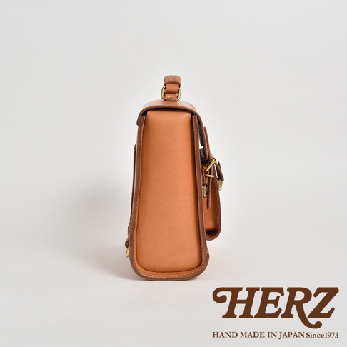 經典學院風迷你後背包，採用天然皮革手工製作，呈現溫潤的焦糖棕色，設有金屬扣環和提把。