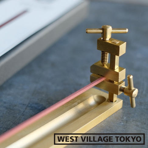 黃銅夾式水平線香架，設有可調節夾具，可固定粉紅色線香，置於長條形黃銅底座上。