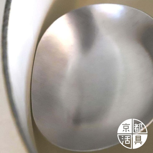 不鏽鋼萬用料理大勺的勺面，呈現拉絲紋理的銀灰色，勺緣邊緣有細微的光澤。