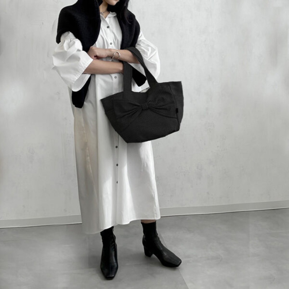 黑色三河木綿刺子織托特包，包身正面飾有蝴蝶結造型，材質紋理清晰可見。