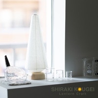 帶有木質底座的白色錐形紙質提燈，燈罩上有細密的網格紋理。提燈旁是三個透明玻璃燒杯，其中最大的一個標有「200ml」字樣。