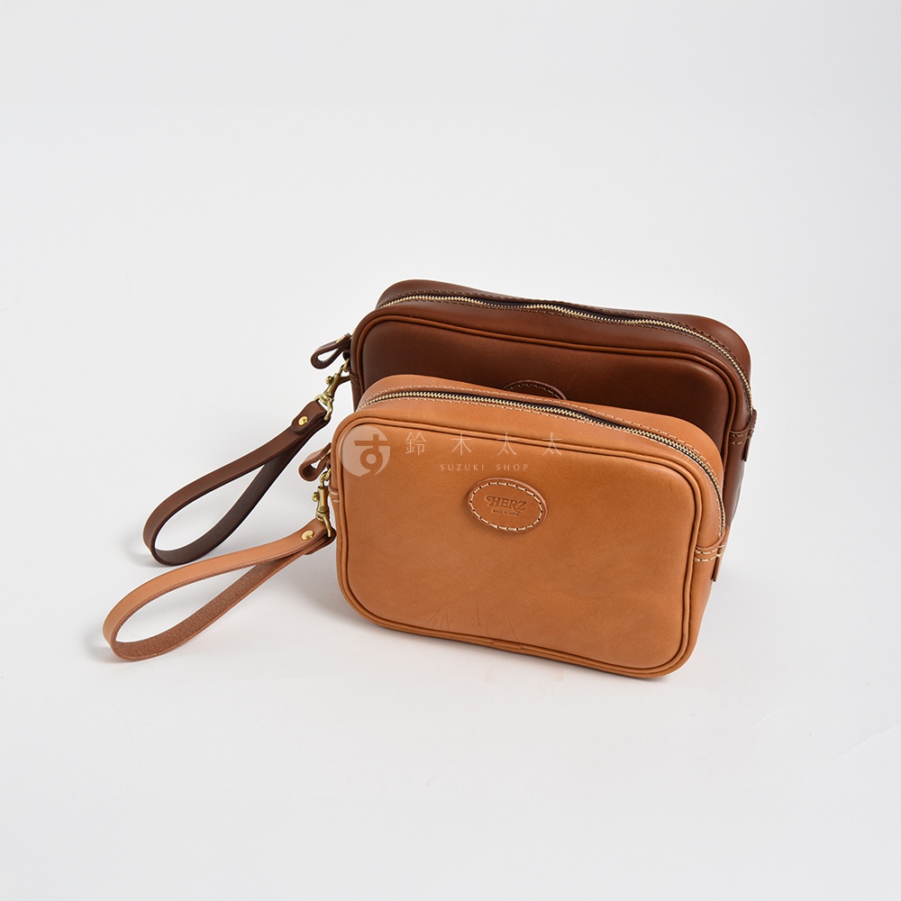 兩款皮革手提包，一款為淺棕色，另一款為深棕色，皆配有可拆式皮革腕帶和金色金屬扣環，正面有品牌標誌。