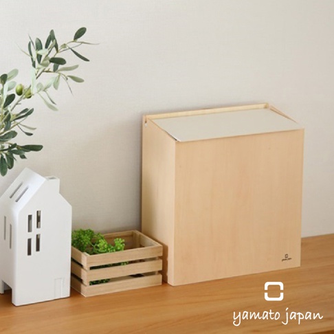 淺木色掀蓋式垃圾桶，容量 8L，側面有品牌標誌，搭配白色房屋造型擺飾與木製小提籃。