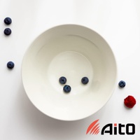 一個簡約的白色陶瓷深碗，碗內有四顆藍莓，碗外左側有三顆藍莓，右側有一顆覆盆子。