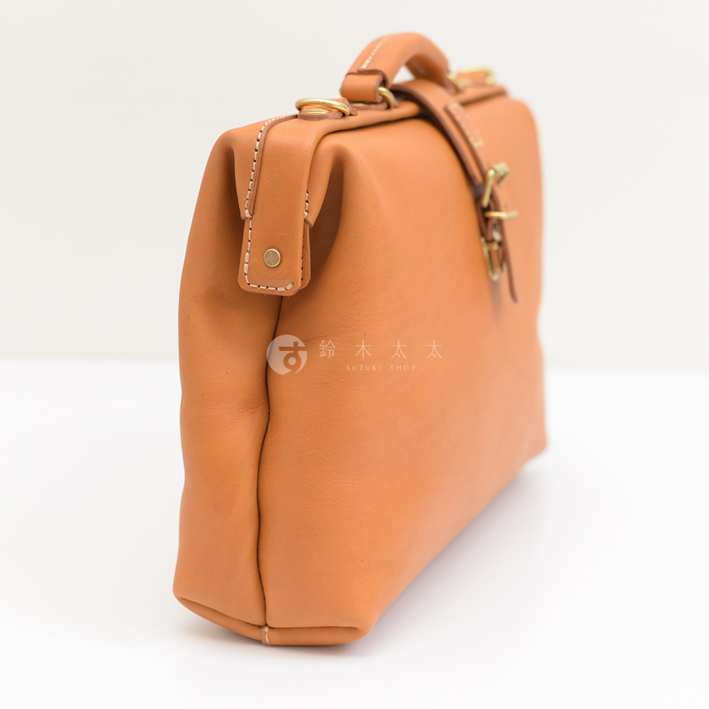職人手作皮革軟式杜勒斯包，淺棕色，採用光滑皮革材質，設有提把、金屬扣環及磁吸式開合，包身線條簡潔，側面縫線清晰可見。