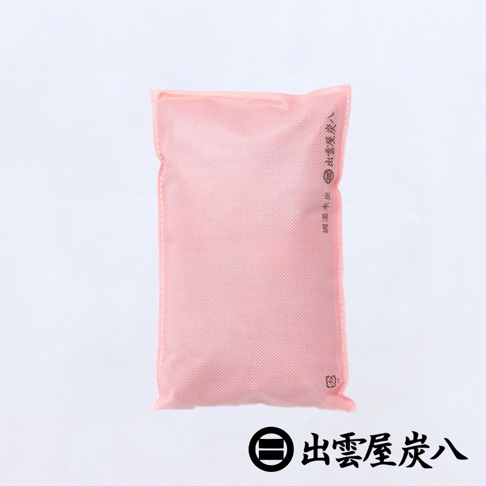 一個粉紅色的出雲屋炭八櫥櫃專用寬版調濕木炭，採用雙層不織布材質包裝，袋面印有品牌文字，整體設計簡約實用，適合用於衣櫥或鞋櫃等空間進行除溼與除臭。