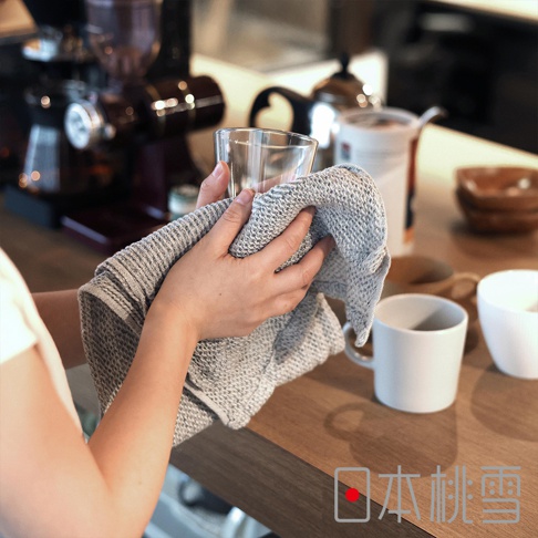 日本桃雪品牌標誌疊加在檜木鬆餅紋毛巾擦拭玻璃杯的圖片上