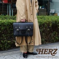 黑色皮革三用學生包，帶有金色扣環和可調節皮帶，可肩背或後背，呈現傳統歐風設計。