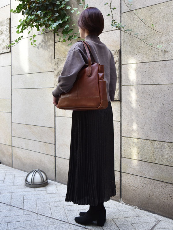 棕色皮革直式托特包，配有可肩背的提把，包身線條簡潔，風格經典。