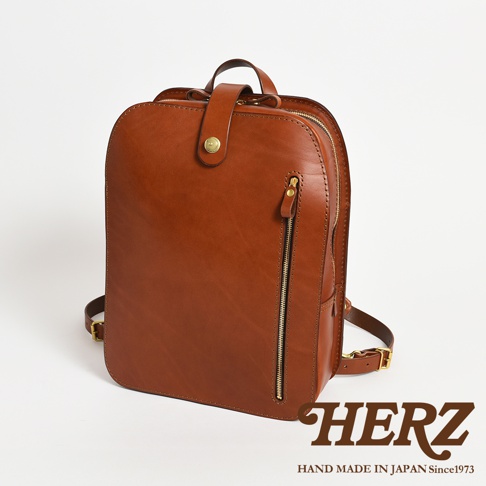 職人手作皮革商務休閒兩用後背包，採用光滑的棕色皮革製成，配有金色拉鍊和釦子，設計簡潔大方，適合日常商務及休閒場合使用。