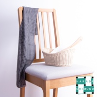 淺灰色網格紋沐浴巾搭在木椅上，椅上擺放著一個藤編籃，籃內有一條白色毛巾和一個木柄。