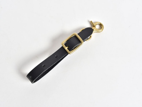 黑色皮革製成的手作可調式吊掛帶，配有黃銅色金屬鉤扣和方形調節環，帶有兩個調節孔。