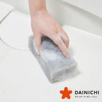 手拿灰色粗孔海綿，正在清潔白色表面，海綿上沾有泡沫。