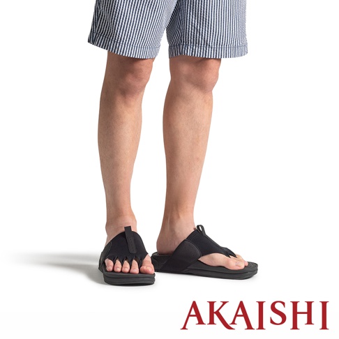 一位穿著藍白細條紋短褲的模特兒，雙腳穿著黑色 AKAISHI 五指放鬆伸展拖鞋，以斜側面視角展示拖鞋將腳趾分開的特殊設計，整體為簡潔的商品形象照。