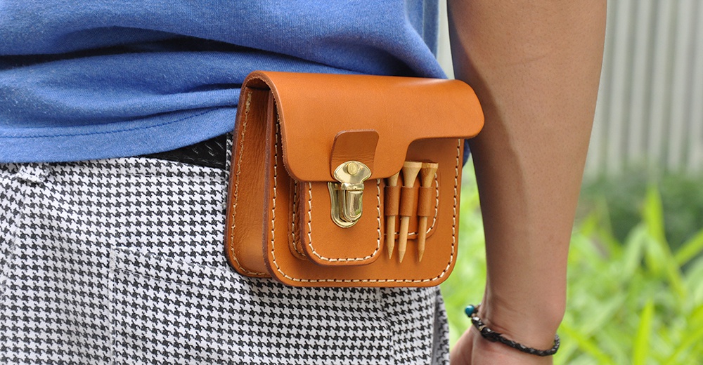 棕色皮革製作的職人手作高爾夫腰包，附有金屬旋鎖和可插入高爾夫球釘的側邊插槽。