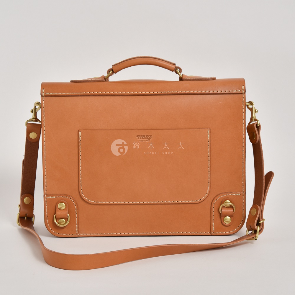 焦糖色皮革製成的手提公事包，帶有可拆卸肩帶、頂部提把、前置翻蓋口袋，並飾有品牌標誌和金屬配件。