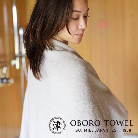 一位女性肩上披著淺灰色細纖浴巾，浴巾質地柔軟，擁有摩登復古風格。