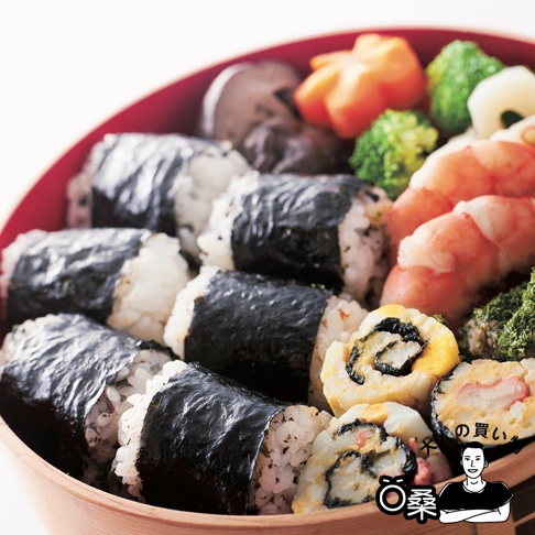 紅底木紋餐盒中，擺放著數個被深棕色海苔包裹的飯糰，飯糰內可見米飯與少許調味料。餐盒另一側有對切的玉子燒捲、蝦仁、花形紅蘿蔔、綠色花椰菜與深色菇類。