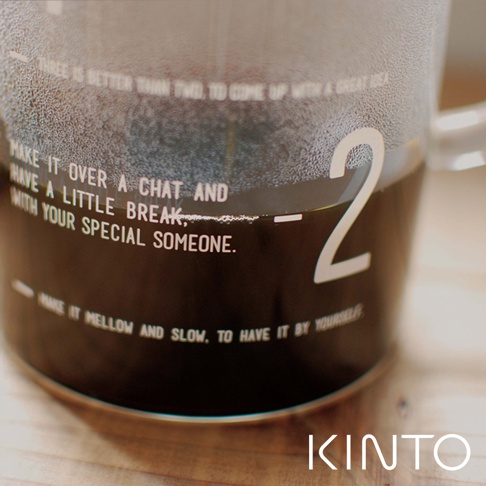 透明玻璃咖啡沖泡壺，壺身有白色文字和數字「2」，內部裝有深色液體，壺壁佈滿細小水珠。