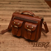 職人手作棕色皮革雙口袋兩用單肩包，配有金屬釦環和拉鍊，可肩背或手提。