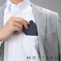 手持一個深藍色的摺疊環保隨行袋，放入白襯衫的胸前口袋。隨行袋材質光滑，邊緣清晰，展示其小巧便攜的特性。