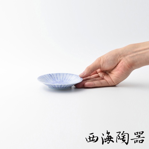 一只手托著一個白色陶瓷小豆皿，皿上飾有藍色細緻的十草紋。
