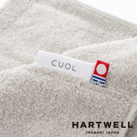 淺灰色 CUOL 品牌標籤縫製於柔軟、絨毛感的美髮毛巾上，毛巾質感細緻，觸感柔順，側面可見 HARTWELL IMABARI JAPAN 字樣。