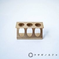 淺棕色紙質試管瓶放置架，有三個圓形孔洞，可容納試管瓶，結構簡潔，放置於白色背景上。