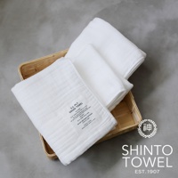 籃子裡疊放著三條純白色2.5層紗浴巾，材質柔軟，表面有細緻的織紋。