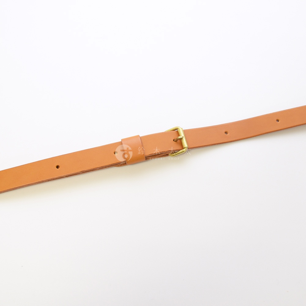 一條卡其色皮革製成的細長肩背帶，帶有金色釦環和可調節孔洞，背景為白色。