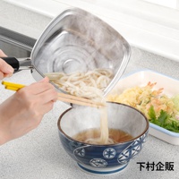 一只手持著帶有麵條的銀色方形單手麵鍋，準備將麵條倒入藍白花紋的碗中。旁邊有一個裝有天婦羅的白色盤子。