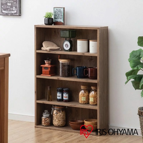 淺木紋四層收納書櫃，頂部擺放裝飾植物、磅秤、兩個白色儲物罐。第二層有咖啡研磨機、玻璃罐裝咖啡豆、藍色及紅色馬克杯。第三層有玻璃瓶、兩罐果醬、兩個玻璃罐裝零食。最底層有兩個玻璃罐裝穀物、兩個木碗。